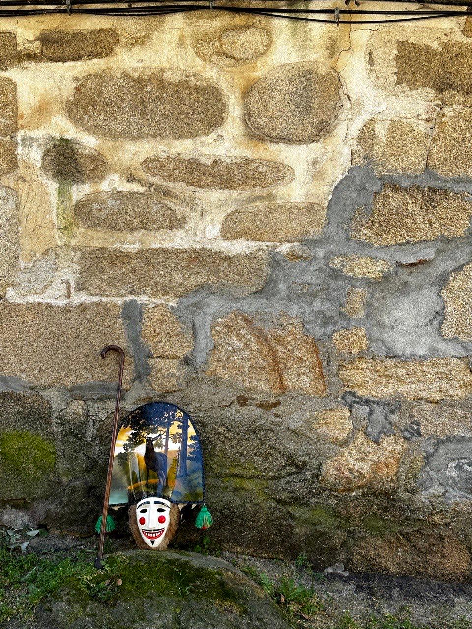 Máscara tradicional del entroido gallego junto a una pared de piedra